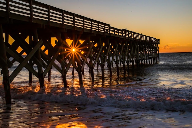 Silhouette built structure on beach against sky during sunset