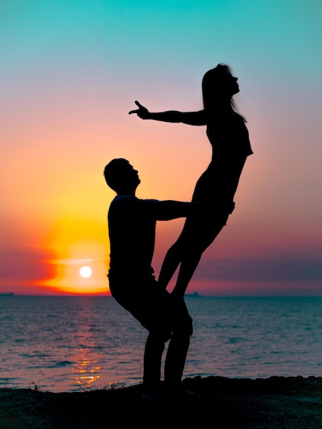 Photo silhouette couple exercising at beach against sky during sunset