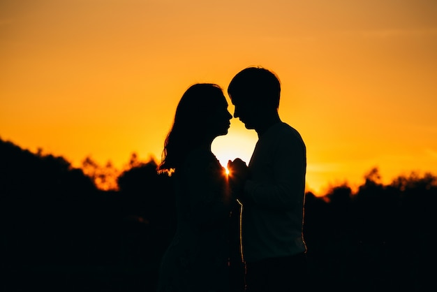 Silhouette of a couple in love on background of an orange sunset in summer