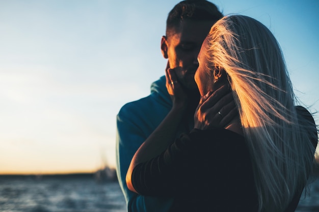 Silhouette of couple in love on the pier, sunset time