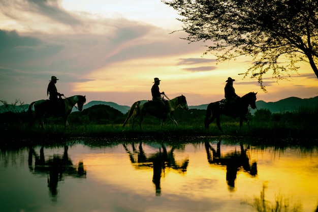 Silhouette the cowboy riding on a mountain with an yellow sky.