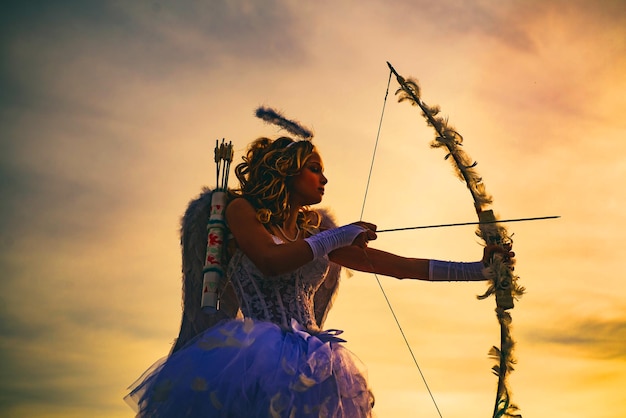 Silhouette of a cupid side view of teen girl archer against sunset little cupid girl aiming at someo...