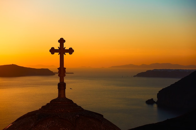 Silhouette of cupola with cross of Greek Orthodox Church and the sea in the background after sundown. Fira town, Santorini, Greece. Landscape