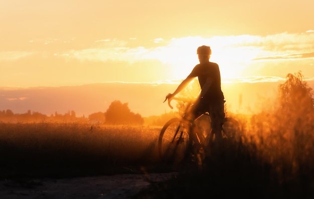 Silhouette of Cyclist on a countryside dirt road at sunset