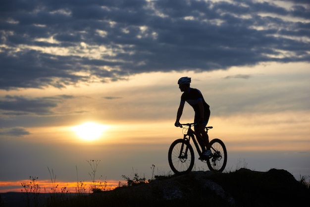 Silhouette of cyclist standing on bicycle