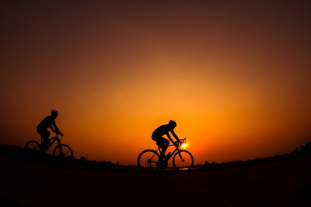 Silhouette of cyclist in sunset background.