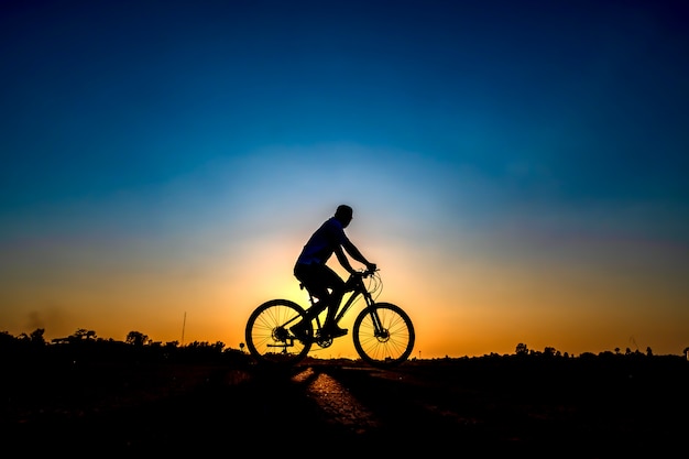 Silhouette of cyclist in sunset background.