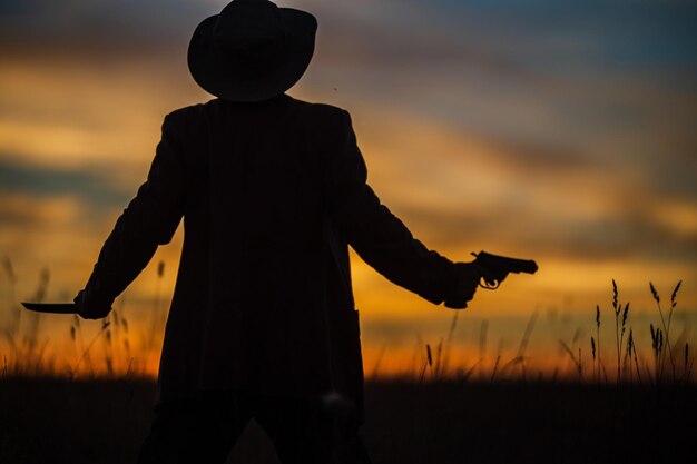 Silhouette of a demon and vampire hunter with a dramatic sky in the background A man with a katana and a revolver Fantasy and halloween concept