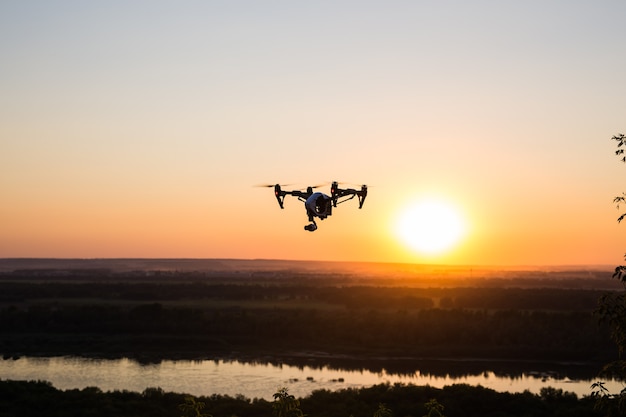 Silhouette of drone, quadrocopter with photo camera flying in the sky.