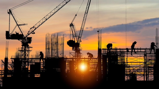 Silhouette of Engineer and worker on building site construction site at sunset in evening time