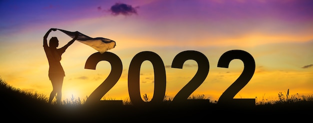 Silhouette enjoying women flapping a thin fabric on the hill while celebrating 2022 years