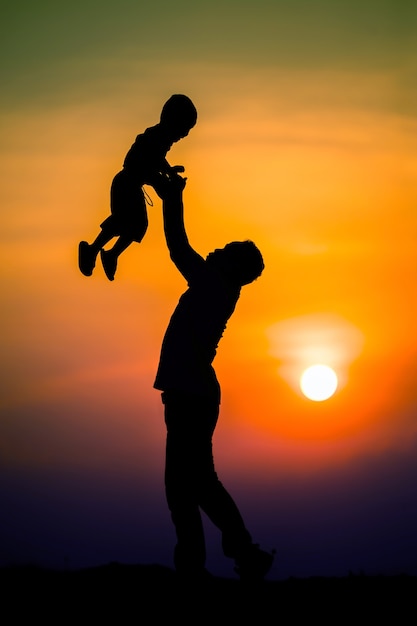 Silhouette of the family that the father is playing with the boy happily with the sunset sky