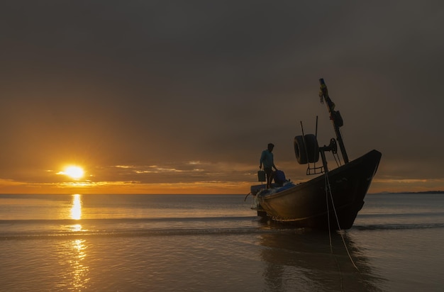 Silhouette fisherman on the boat on the beach