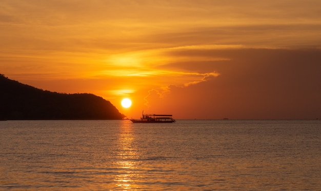  silhouette fisherman boat floating on sea during  golden sunset with the sun reflect on water