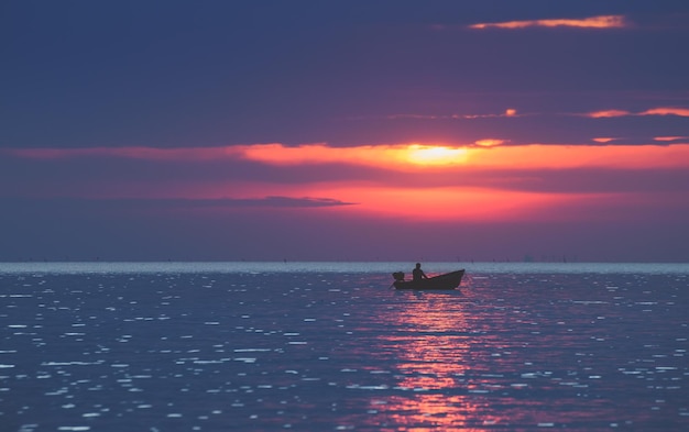 Silhouette fisherman on the boat in the sea