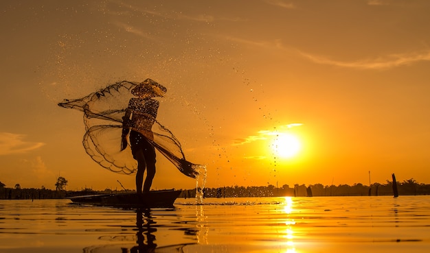 Silhouette Fisherman Fishing Nets on the boat.Thailand