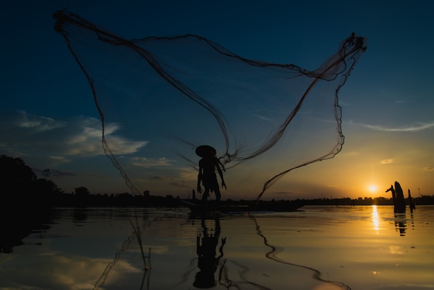 Silhouette Fisherman Fishing Nets on the boat.