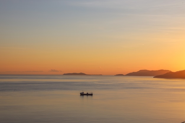 Silhouette of fishing boat sailing on the sea during sunset