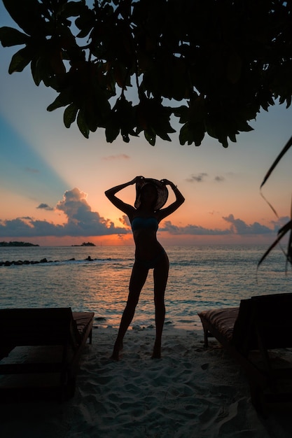 Photo silhouette of fit girl posing on tropical beach on ocean shore with sunset in maldives with skyline