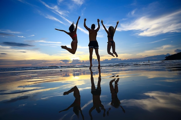 silhouette of friends sunset sea summer / group of young friends men and women in summer have a rest and have fun on the sea, happy sea sunset