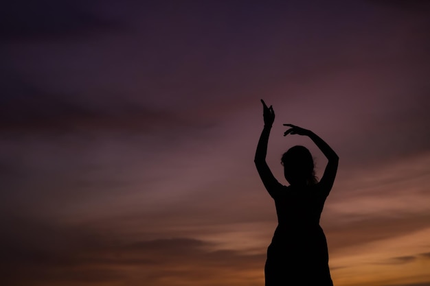 A silhouette of a girl dancing at sunset