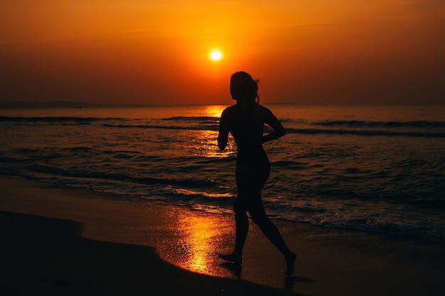 Silhouette of a girl running by the sea on the beach