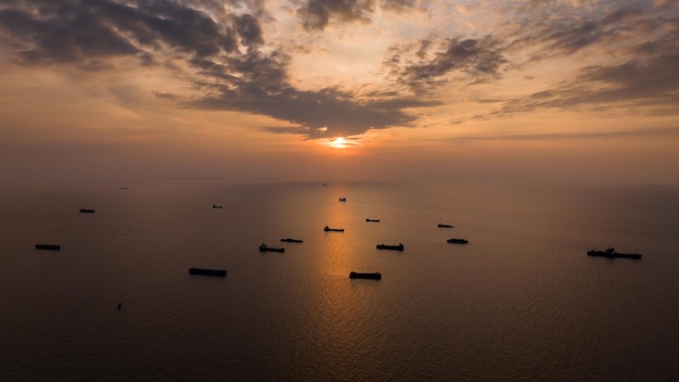 Silhouette group of Container ship floating in middle sea and over the sunset background