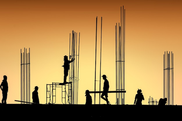 Silhouette group workers on building site with sunset sky in the evening