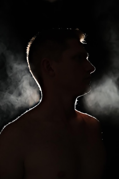 Silhouette of a guy men in the dark smoke steam man in a dark room