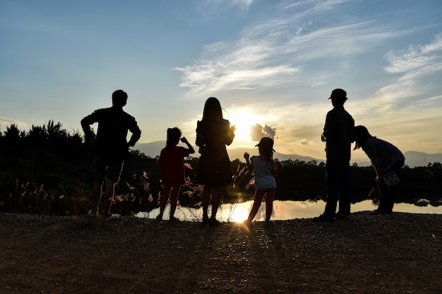 Silhouette of a happy family at the dam while sunset with blue sky.