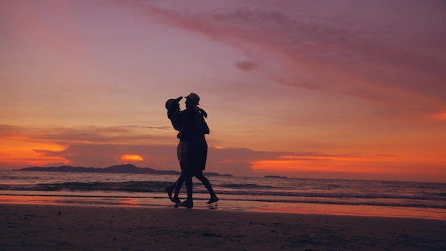 Silhouette of happy loving couple meet and play at the beach on sunset in ocean shore