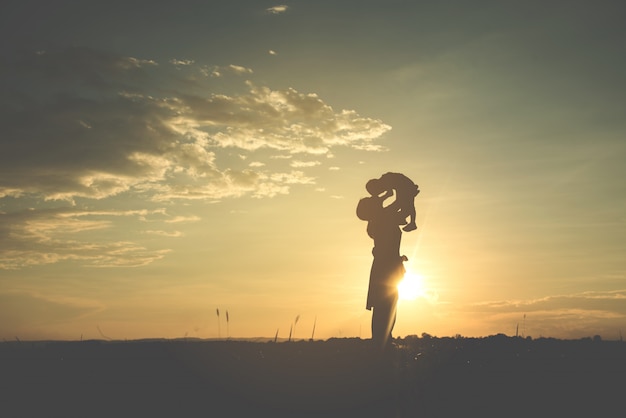 A silhouette of a happy young mother harmonious family outdoors. 