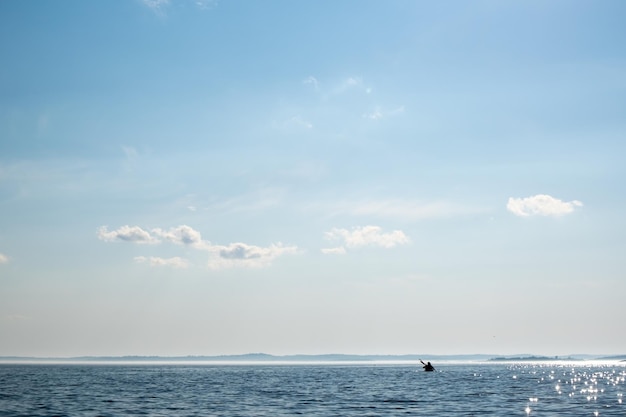 Silhouette of a kayak with tourists floating on the lake against the horizon