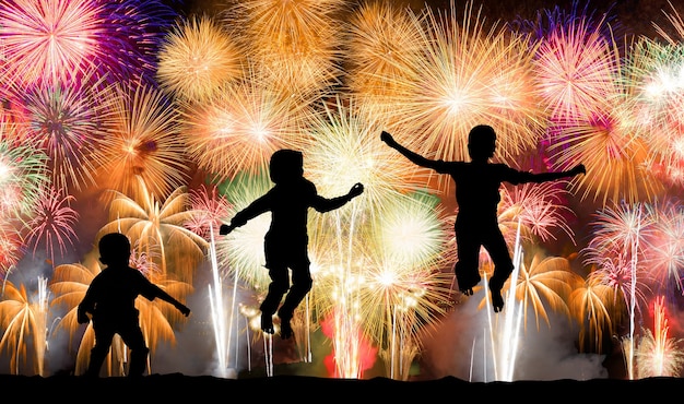 Photo silhouette of kids jumping over colorful firework