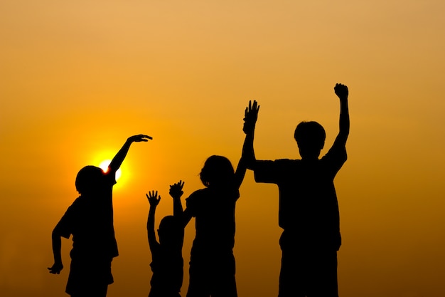 Silhouette of kids playing together with sunset