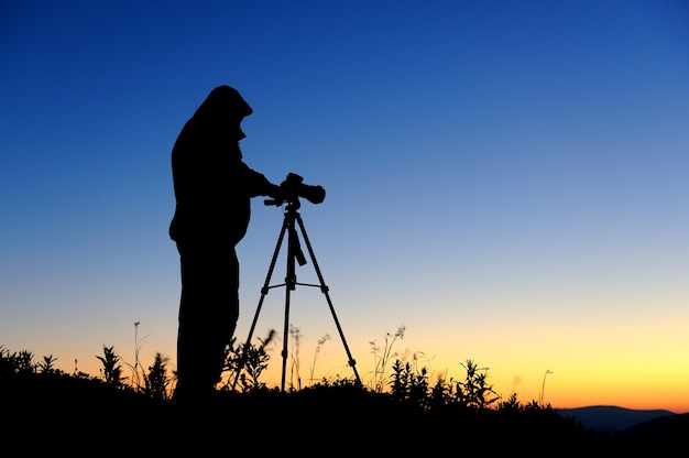 Silhouette of a landscape photographer in twilight