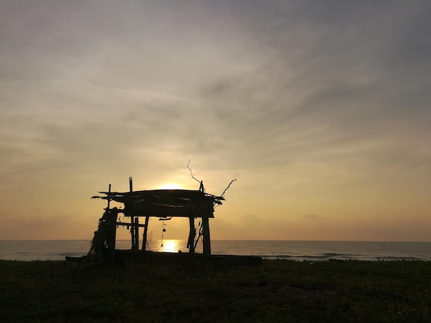 Photo silhouette lifeguard hut on beach against sky during sunset