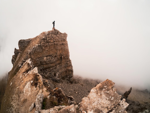 Silhouette of a lone tourist over a cliff Sharp rocks Mystical