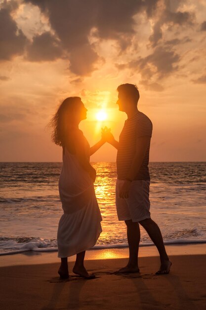 Silhouette lovely couple holding hands on tropical sandy beach at sea sunset background Happy man and woman looking happiness