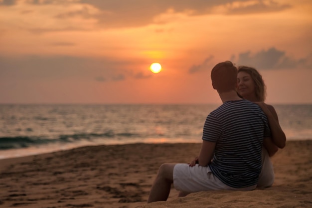 Silhouette lovely couple sitting on tropical sandy beach at sea sunset background Happy man and woman smiling happiness