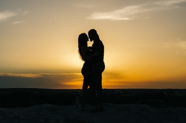 Photo silhouette of a loving couple embracing at sunset