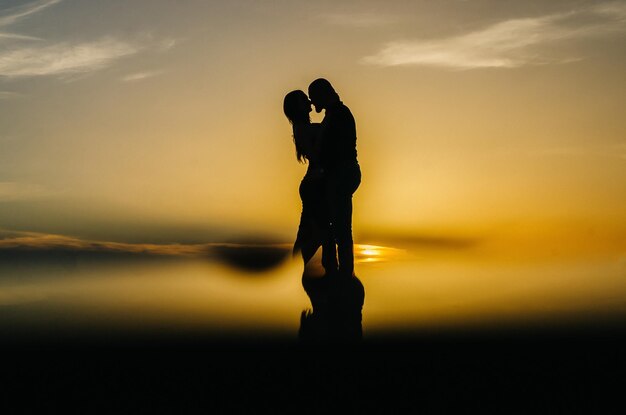 Photo silhouette of a loving couple embracing at sunset