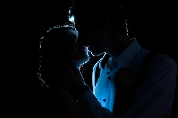 Silhouette of loving couple with a blue light behind. Studio photo