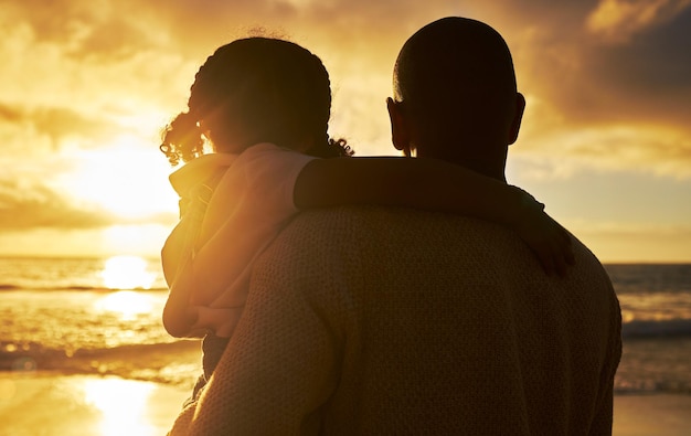 Silhouette of a loving father and daughter watching the view at sunset Family looking at the beautiful golden sky while on holiday Little girl and dad bonding and enjoying time together on vacation