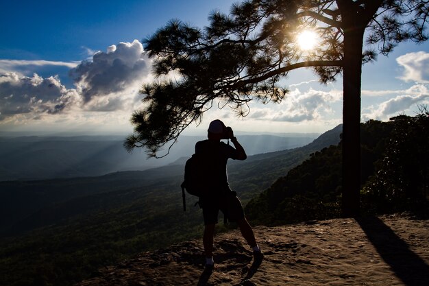  silhouette A man asia with backpack taking a photo on the top of mountains ,soft focus