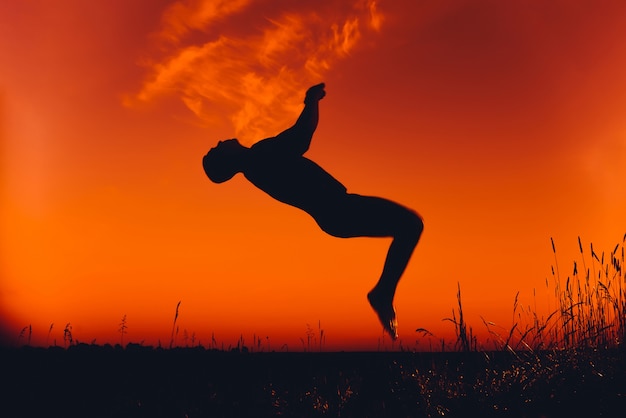 Silhouette of a man doing a back flip at sunset