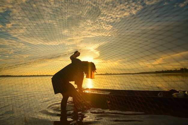 Silhouette of a man doing traditional Thai traditional fishing in the river. In Chiang Mai, Thailand 12/05/2021