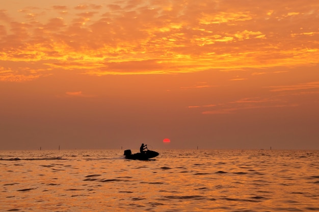 Silhouette of man driving jetski on the sea with during sunset