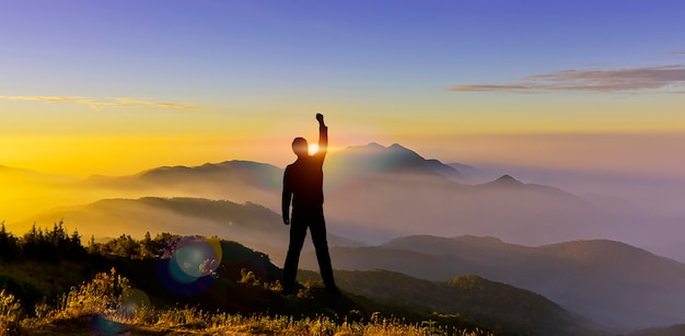 Silhouette man hand up on mountain show startup fight goal change challenge success concept