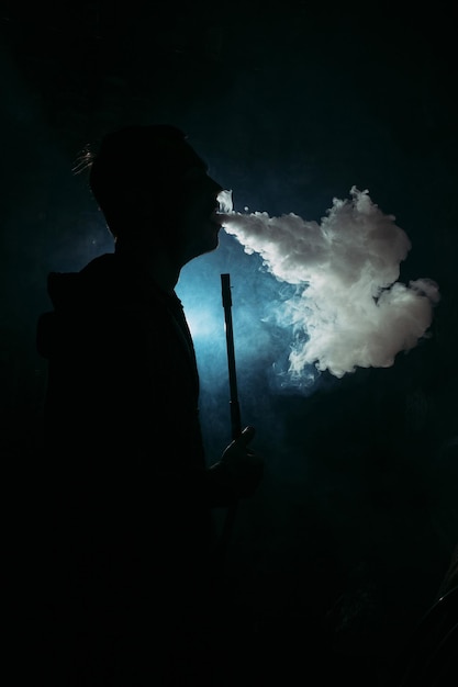 Silhouette of a man inhaling smoke from a hookah background